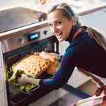 mujer riendo sacando el plato del horno