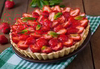 tart with strawberries and whipped cream decorated with mint leaves