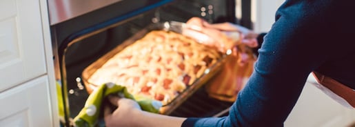 la mujer saca el plato del horno